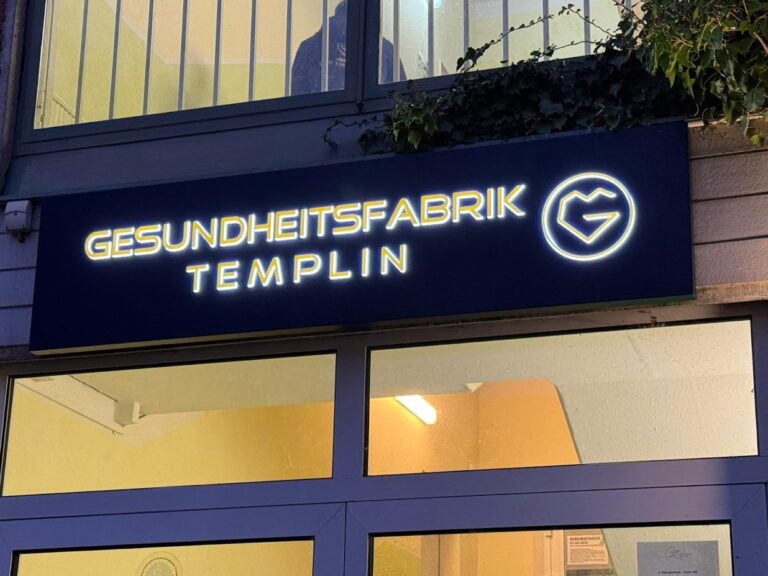 Leuchtende Außenwerbung der Gesundheitsfabrik Templin am Abend